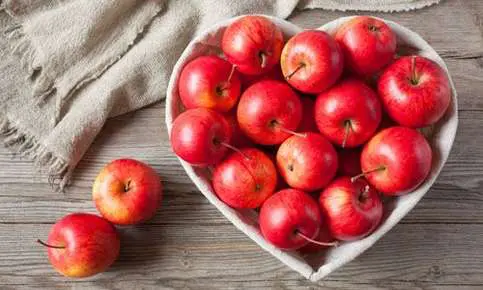 Fresh apples in heart-shaped dish