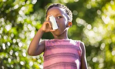 Kid breathing with inhaler in sunlight