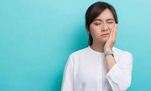 Female in discomfort touching her face