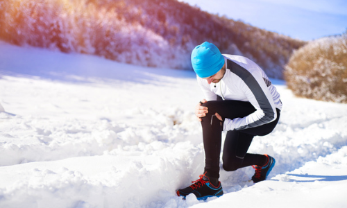 Man adjusting gear in snowy terrain