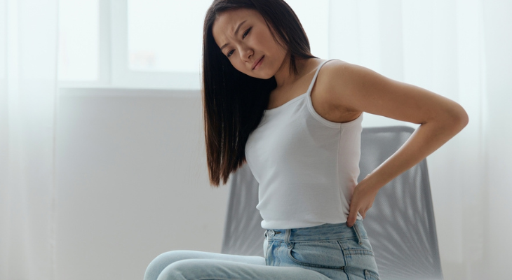 Person in discomfort holding lower back