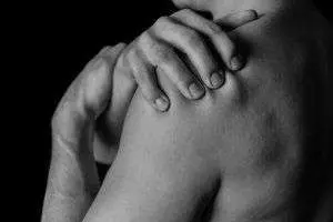 Hands touching bare shoulder in black and white