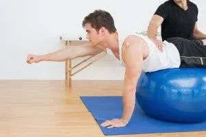 Fitness trainer assisting with balance exercise