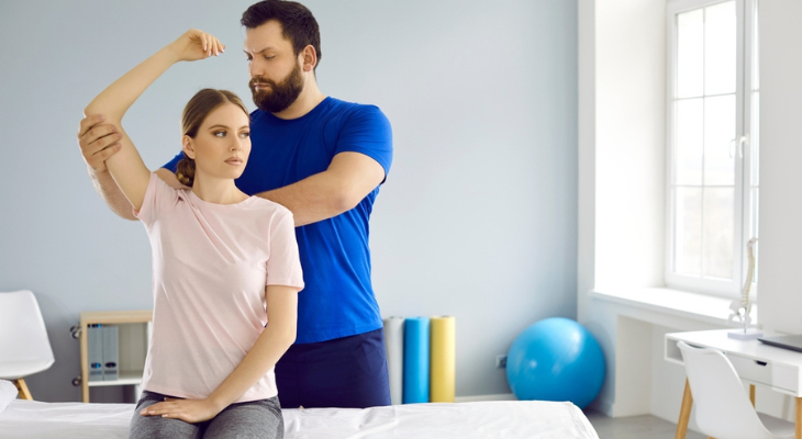 Physical therapist assisting woman's arm stretch
