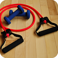 Resistance band and dumbbells on wooden floor.