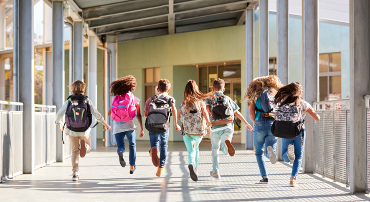 Students joyfully rushing into school building.