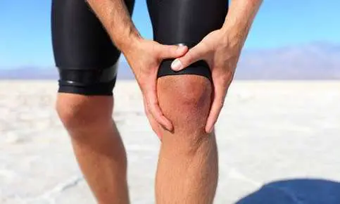 Athlete experiencing knee pain in dry landscape