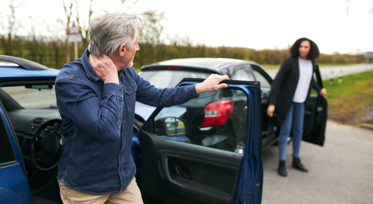 Older man exiting car, woman approaching