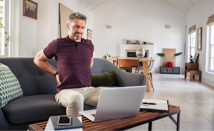 Man experiencing back pain on sofa