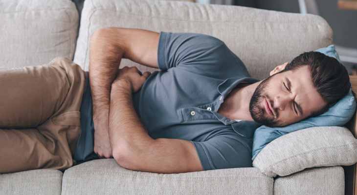 Man lying on couch in pain