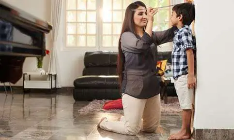 Woman marking child's growth on wall