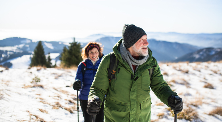 Elderly couple hiking in snowy mountains
