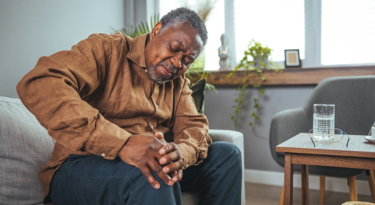 Man experiencing knee pain on couch