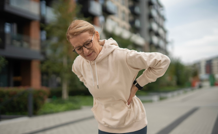 Woman in hoodie with back discomfort