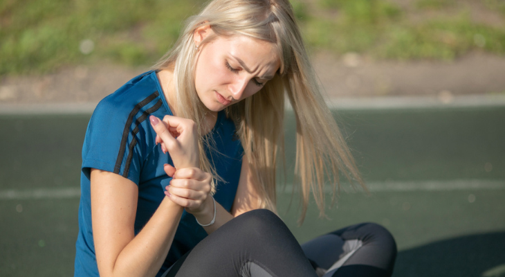 Blond woman examining her wrist injury