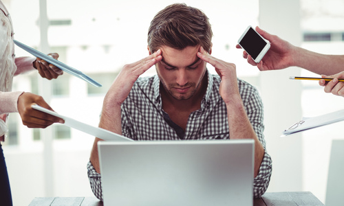 Overwhelmed employee at a busy desk