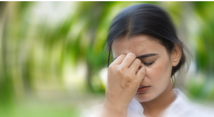 Pensive woman touching forehead outdoors