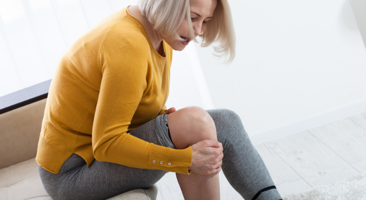 Woman holding knee in discomfort