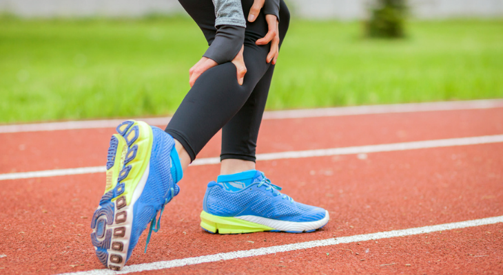 Runner stretching on track with blue shoes