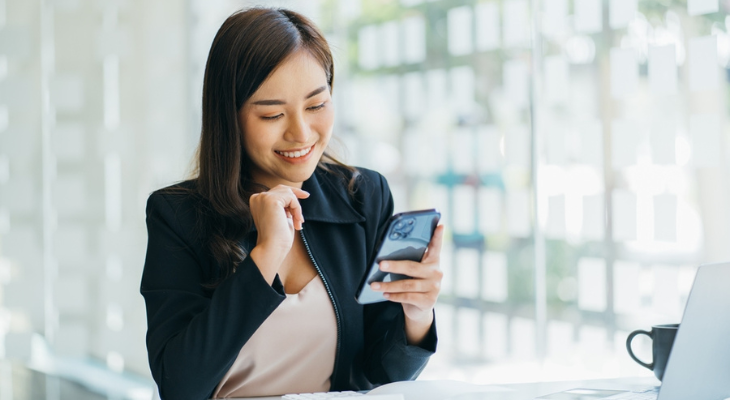 Woman smiling at phone in office