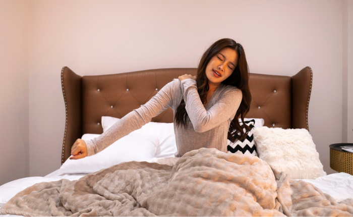 Woman stretching in bed with cozy blanket.