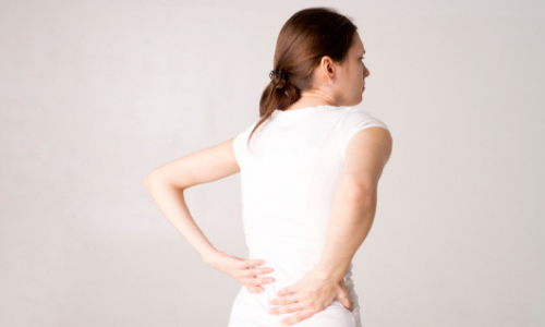 Person experiencing discomfort in the lower back.