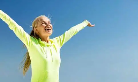 Joyful woman with arms raised outdoors