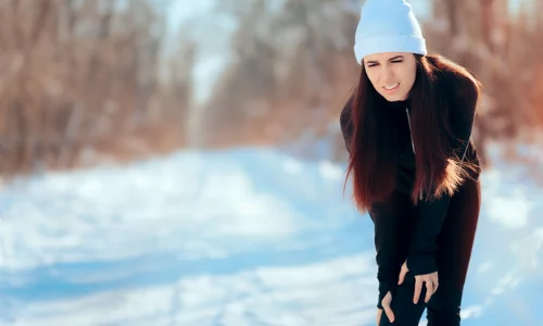 Woman holding knee on snowy path