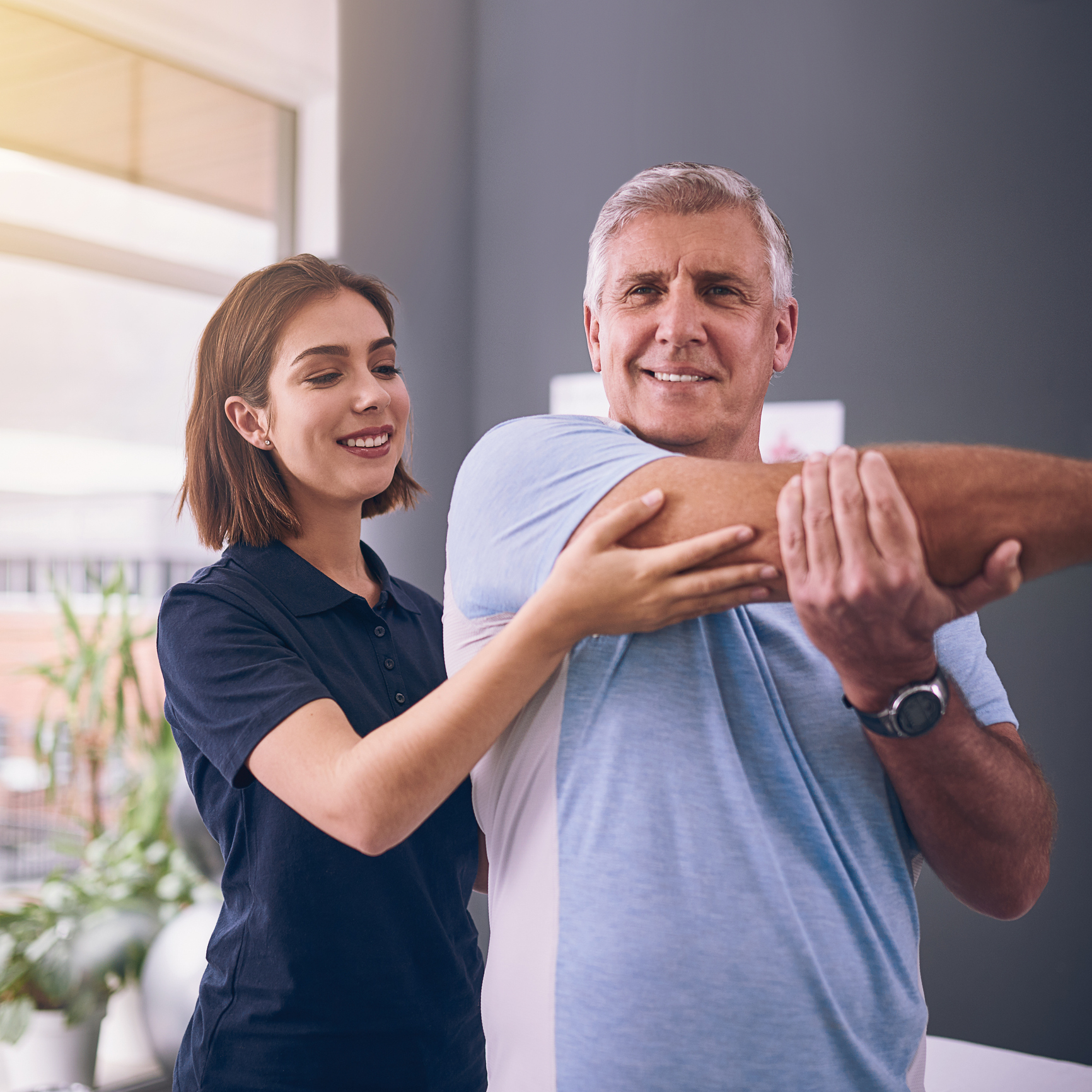 Therapist aiding senior with exercise