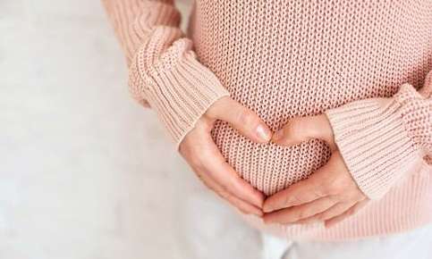 Pregnant woman forming heart on belly