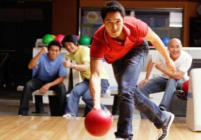 Person rolling bowling ball, friends watching