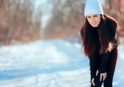 Woman holding knee on snowy path