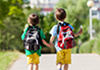 Two boys walking towards school together.