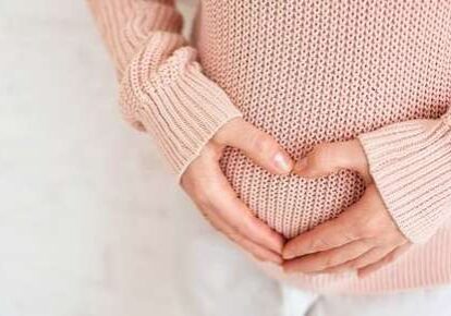 Pregnant woman forming heart on belly