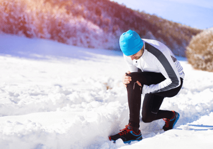 Man adjusting gear in snowy terrain