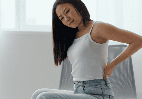 Person in discomfort holding lower back