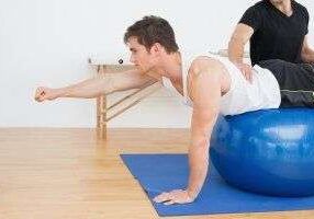 Fitness trainer assisting with balance exercise
