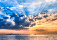 Sunset over calm ocean with clouds