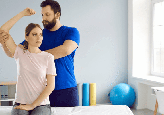 Physical therapist assisting woman's arm stretch
