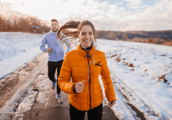 Smiling runners exercising in winter landscape