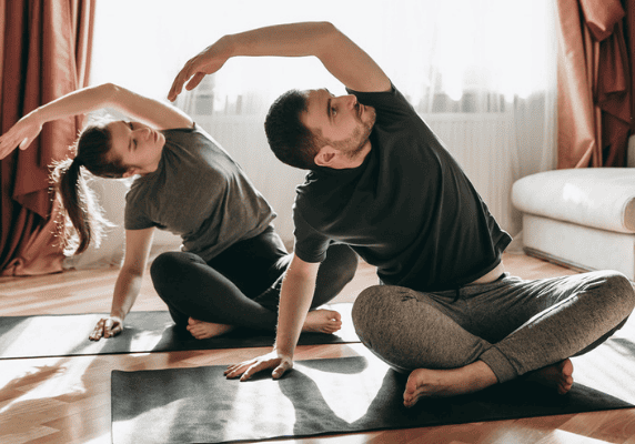 Couple practicing yoga at home