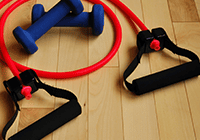 Resistance band and dumbbells on wooden floor.