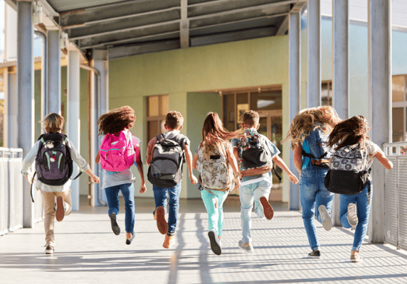 Students joyfully rushing into school building.