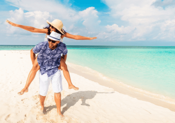Man carrying woman on sandy shore