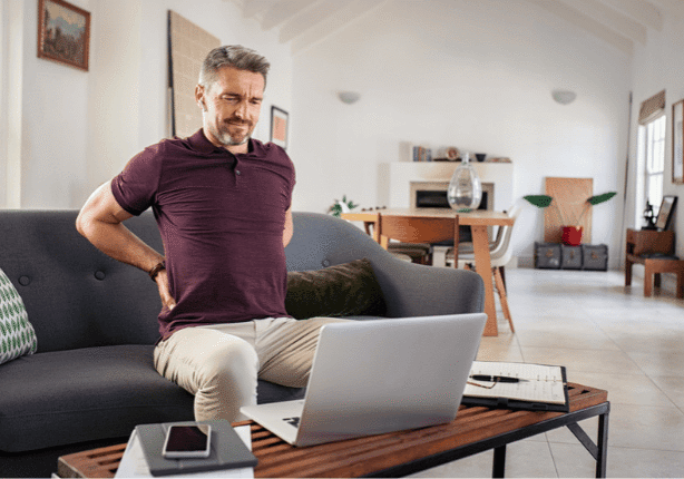 Man experiencing back pain on sofa