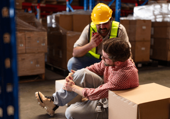 Colleague assisting injured worker in warehouse