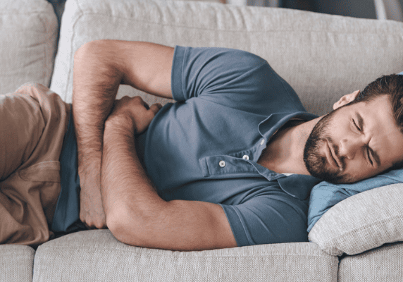 Man lying on couch in pain