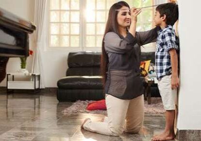 Woman marking child's growth on wall