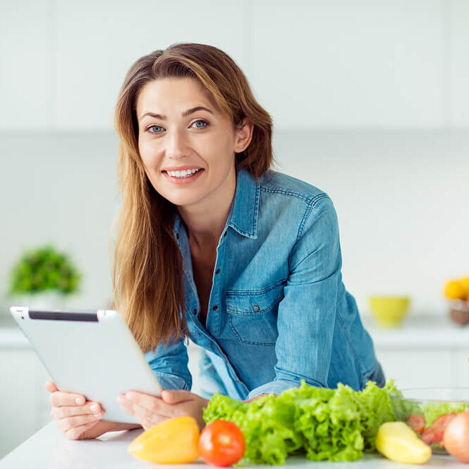 Smiling woman preparing meal with vegetables