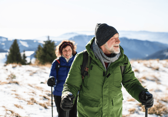 Elderly couple hiking in snowy mountains